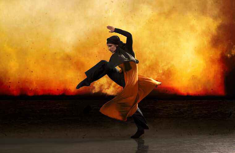 A performer dances across the stage on an orange background.