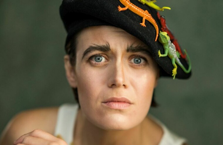 Headshot of Serena Flynn wearing a hat covered in plastic lizards.