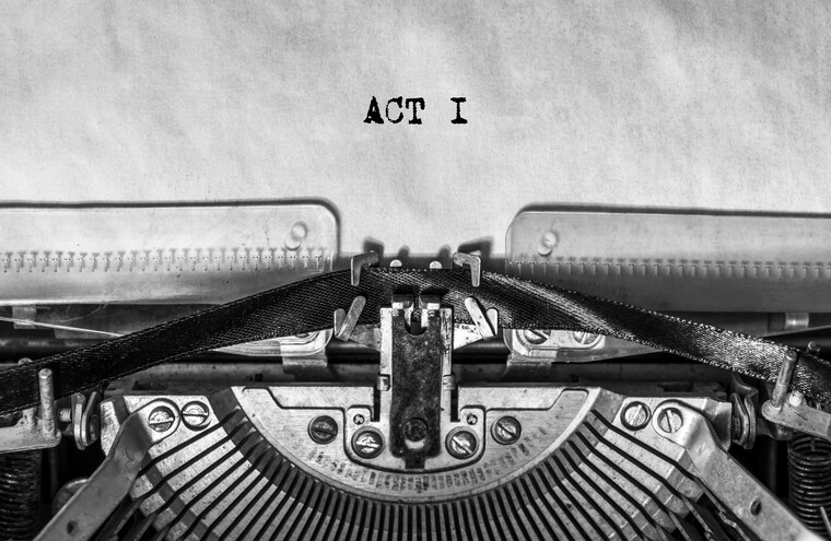 Closeup of an old typewriter. The sheet of paper has the words ACT 1 printed on it.