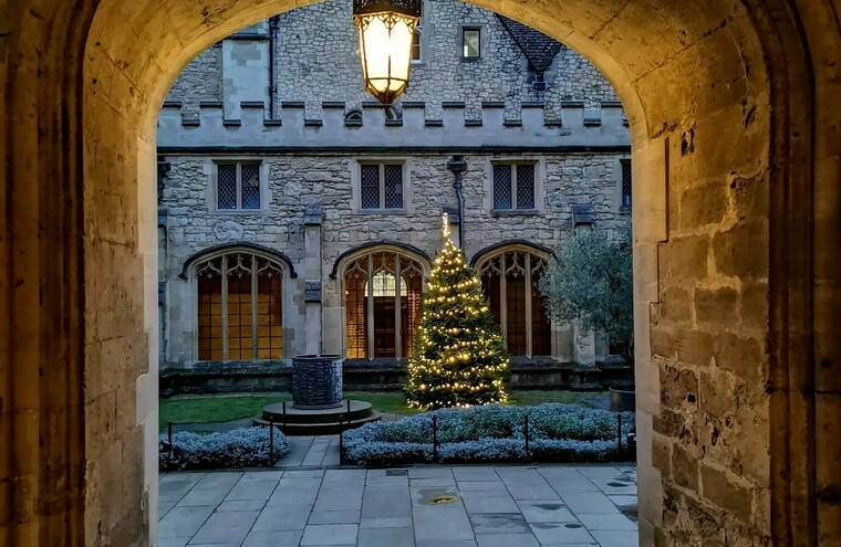 A college quad seen through an arch with a Christmas tree in the middle